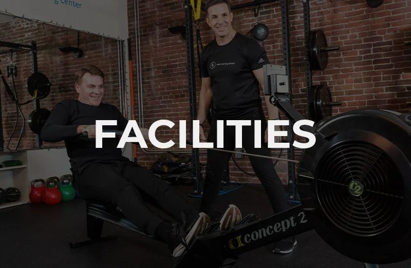 Two men are in a gym; one is using a rowing machine while the other stands nearby, both smiling. The word “FACILITIES” is prominently displayed over the image.