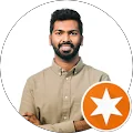 unnamed (2) A man with dark hair and a beard, wearing a beige button-up shirt, stands with arms crossed in front of a plain white background. An orange star badge is displayed in the corner.
