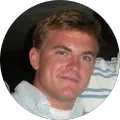 unnamed (3) A man with short light brown hair and a light complexion is wearing a light-colored collared shirt, looking at the camera and smiling slightly.
