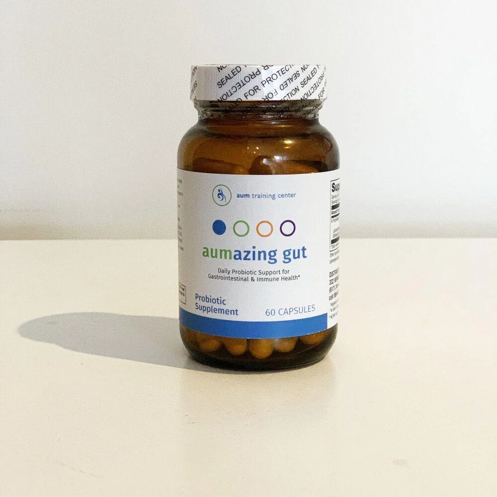 A brown bottle labeled "aumazing gut" probiotic supplement, containing 60 capsules, is placed on a white surface against a plain background.