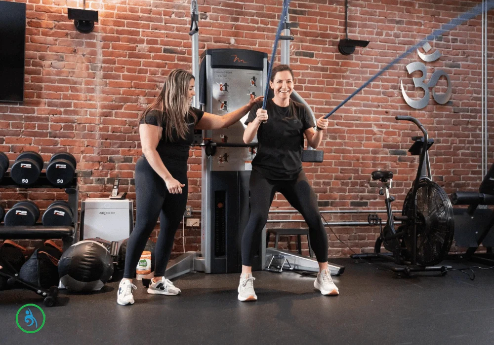 Personal trainer guiding client through resistance band exercise at AUM Training Center in Boston