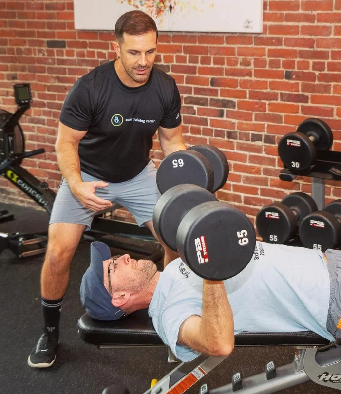 ‘Aum’ is a sacred sound that is known generally as the sound of the universe. Om is all encompassing, the essence of ultimate reality, and unifies everything in the universe. (1000 x 700 px) (600 (3) A man lies on a bench pressing two 65-pound dumbbells while another spots him in a gym with exposed brick walls—an ideal scene for onsite personal training.