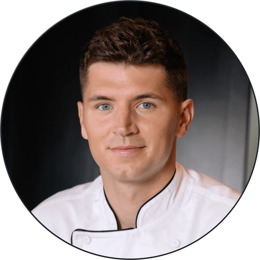 aum-testimonial-digiovanni-v2 Portrait of a young man wearing a white chef’s jacket.