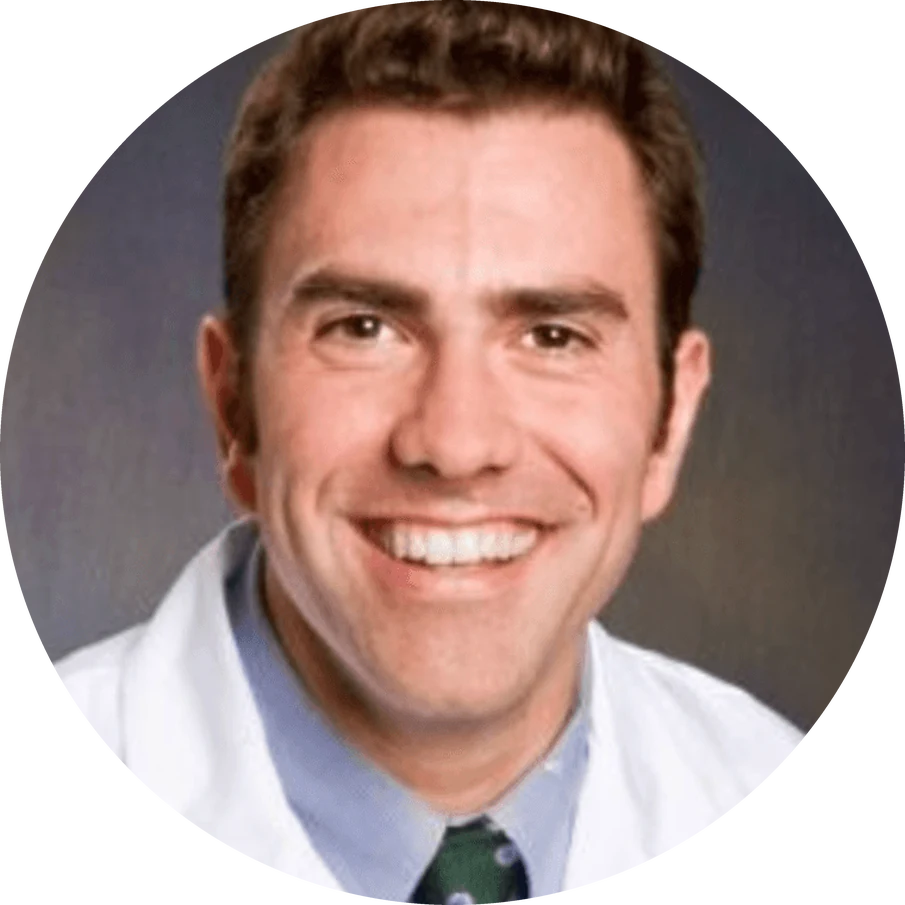 aum-testimonial-merola-v2 Headshot of a smiling man in a white lab coat and a tie.